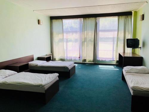 a room with three beds and a flat screen tv at Hotel Koldum in Litvínov