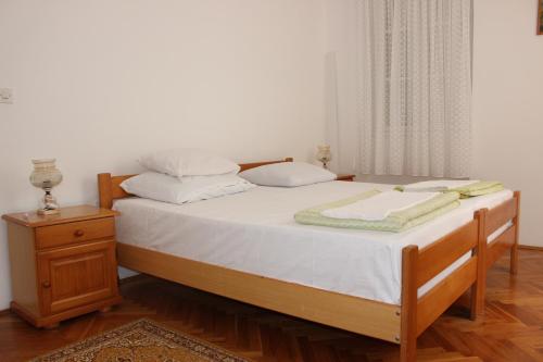 ein Bett mit weißer Bettwäsche und Kissen darauf in der Unterkunft Dudić apartmani in Budva