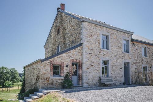 une ancienne maison en pierre avec un banc devant elle dans l'établissement La croisée des champs, gîte entre Durbuy et La Roche en Ardenne, à Érezée
