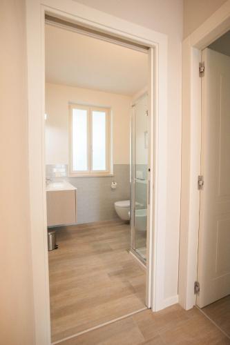 a bathroom with a toilet and a glass door at Italianflat - Maison du Lac in Lazise