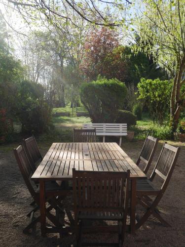 a wooden picnic table with four chairs and a bench at Le Jardin de la Reyssouze in Gorrevod