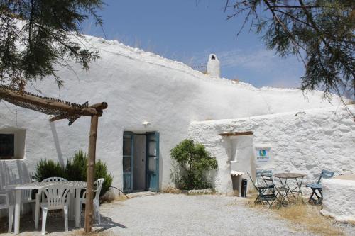 a white building with a blue door and tables and chairs at Cueva El Ermitano in Baza