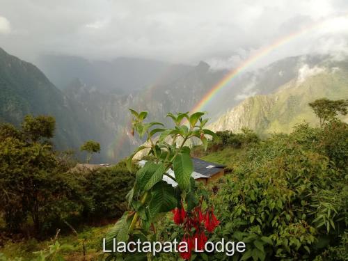 a rainbow in the mountains with a house and a plant at Llactapata Lodge overlooking Machu Picchu - camping - restaurant in Salcantay