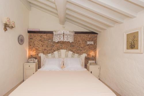 um quarto com uma cama branca e uma parede de tijolos em Charming farmhouse in the hills, private pool, sea view, dream panorama em Camaiore