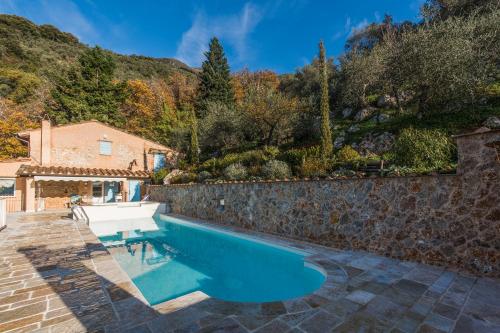 a pool in a backyard with a stone wall and a house at Charming farmhouse in the hills, private pool, sea view, dream panorama in Camaiore