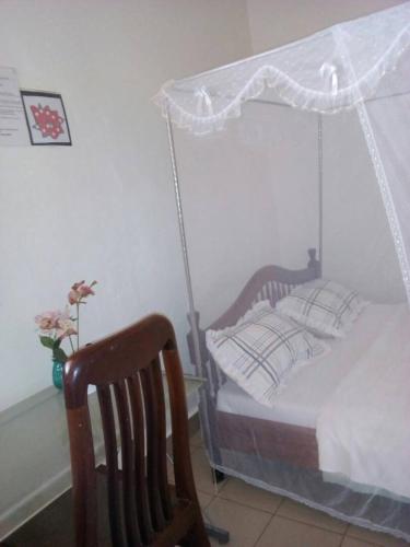 a bedroom with a canopy bed and a chair at Rena Akasha Establishments in Kyenjojo