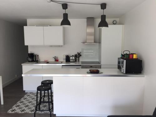 cocina con armarios blancos y encimera con taburete en Appartement Corniche I 40 M2 - 40 M de l'eau ! AU CALME wir sprechen flieBen deutsch, Touristentipps, we speak English en Concarneau