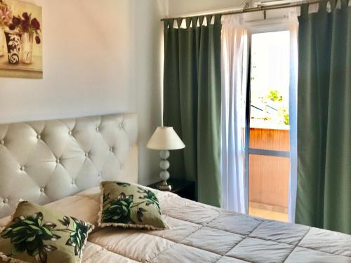 a bedroom with a bed with green curtains and a window at Departamentos temporarios Mirasol lll Federaciòn in Federación
