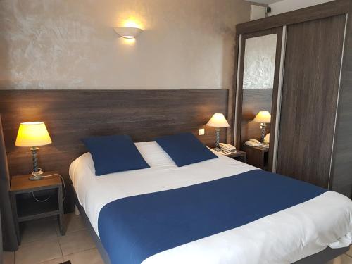 a bedroom with a large bed with blue pillows at Hôtel Ariane in Istres