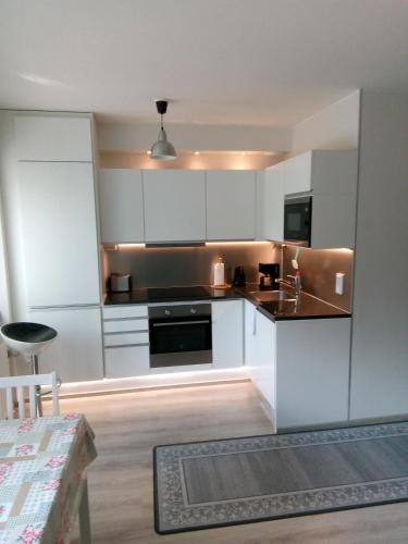 cocina con armarios blancos y estufa negra en Parantolankatu modern one room apartment, en Hyvinkää