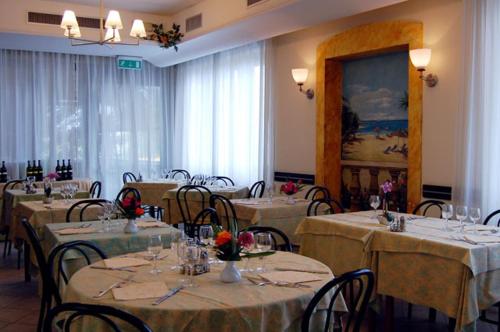 a dining room with tables and chairs with white tablecloths at Hotel Rivamare in Massignano