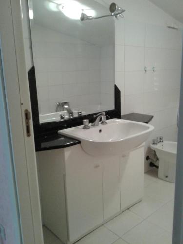 a white bathroom with a sink and a mirror at La mansarda dello scultore in Niscemi