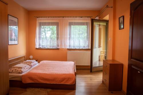 ザコパネにあるApartament Domino - Krzeptówki 06のオレンジ色の壁のベッドルーム1室、ベッド1台、窓が備わります。