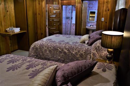 a bedroom with two beds with purple sheets and a lamp at Hotel "La Cabaña de Don Adolfo" in Zacatlán