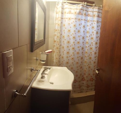 a bathroom with a sink and a shower curtain at Cabañas del Gordo in Mar del Plata