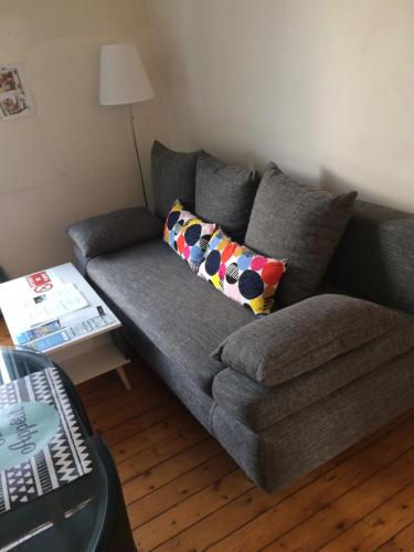 a grey couch in a living room with a table at F2 cosy avec Cour in Milly-la-Forêt