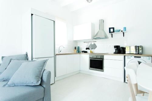 a kitchen with white cabinets and a blue couch at Sun 'n Chill, Boutique Apartments & Beach Villa in Melíkia