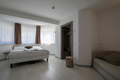 a white bedroom with a bed and a couch at Hotel Luna Bianca Folgaria in Folgaria