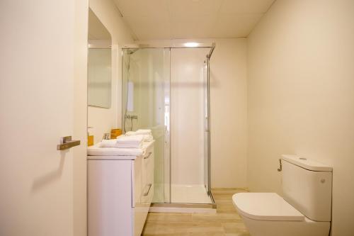 a white bathroom with a shower and a toilet at Malabau Beach House in Tarifa