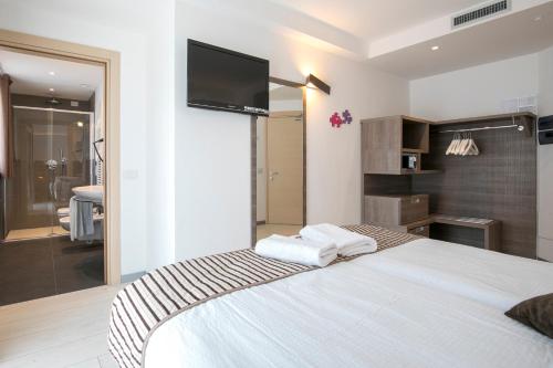a bedroom with a bed with a flat screen tv on the wall at Hotel Luna Bianca Folgaria in Folgaria