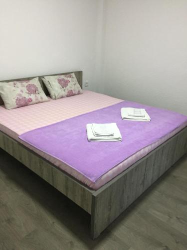a large bed with purple sheets and towels on it at Madzar Apartments in Star Dojran