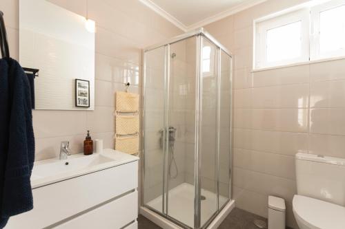 a bathroom with a shower and a toilet and a sink at The Grove l Ericeira Residences in Ericeira
