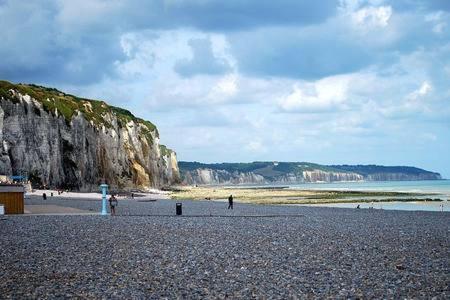 a beach with people standing on a rocky beach at La Maison de Jeanne in Dieppe