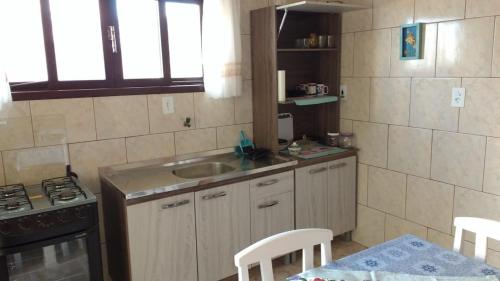uma pequena cozinha com um lavatório e um fogão em Canto da Praia em Itajubá