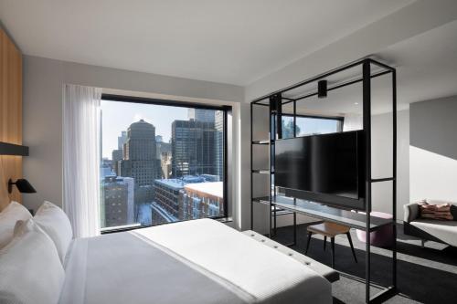 Habitación de hotel con cama y ventana grande en Hotel Monville, en Montreal