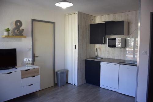 eine Küche mit weißen Schränken und einer schwarzen Arbeitsplatte in der Unterkunft T2 aux pieds des pistes de P2000 in Bolquere