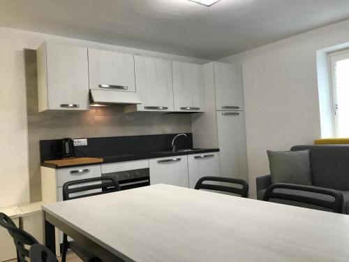a kitchen with white cabinets and a table and chairs at Trentino Apartments - Casa ai Tolleri in Folgaria