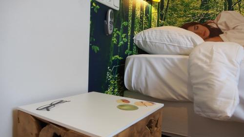 a person sleeping in a bed with a side table at Hotel Het Wapen van Drenthe in Roden