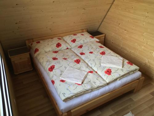 ein Bett in einem Zimmer mit roten Blumen darauf in der Unterkunft Cottage Family in Hrabušice