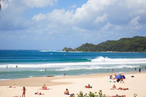 a group of people on a beach near the ocean at Bay Motel in Byron Bay