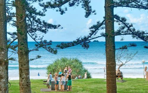 a group of people standing on the beach at Bay Motel in Byron Bay