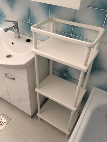 a bathroom with white shelves next to a sink at Apartments Novi Vinodolski in Novi Vinodolski