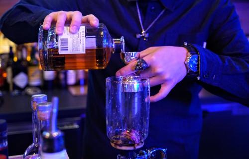 a person pouring a drink into a glass at The Parc Hotel in Queens