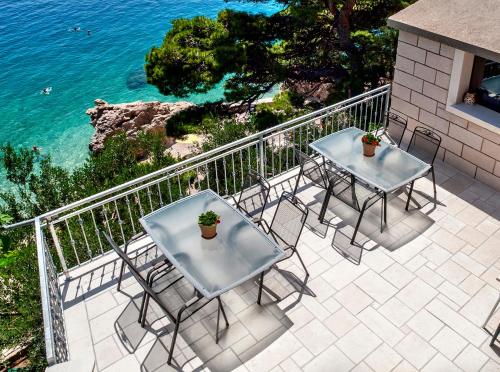 two tables and chairs on a patio overlooking the ocean at Apartmani Lučica in Mimice