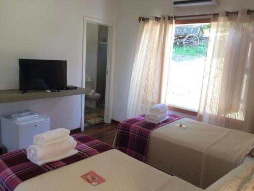a hotel room with two beds and a television at Villa Domaso in Brumadinho