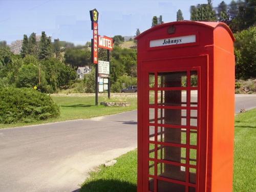 a red phone booth sitting on the side of a road at Johnny's Motel in Grand Forks