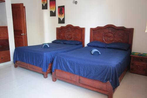 two beds in a bedroom with blue sheets and blue pillows at Villas Roseliz in Punta Allen