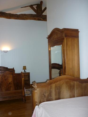 1 dormitorio con cama de madera y espejo en Gîte Le Logis de Faugerit en Frontenay-Rohan-Rohan