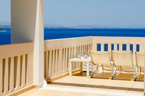 a balcony with a table and chairs and the ocean at Villa Serenity in Porto Rafti