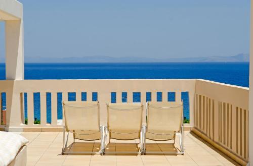 two chairs sitting on a balcony overlooking the ocean at Villa Serenity in Porto Rafti