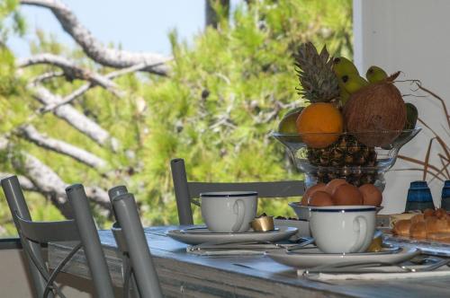 a table with a bowl of fruit and cups on it at Villa Serenity in Porto Rafti