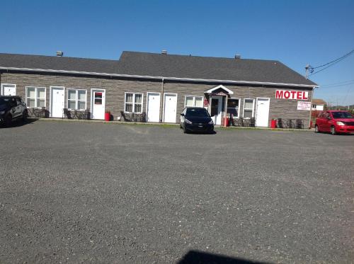 a motel with a car parked in a parking lot at Les studios de la mer in Matane