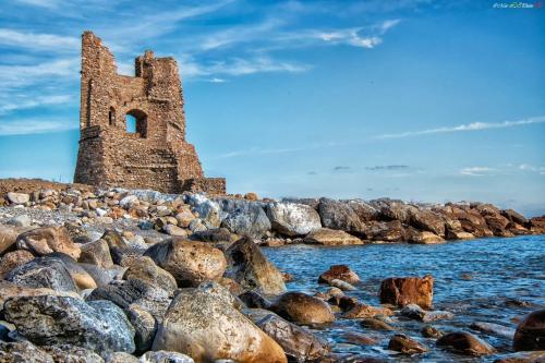 an old tower on the rocks near the water at Il Sogno di Calipso in Amendolara