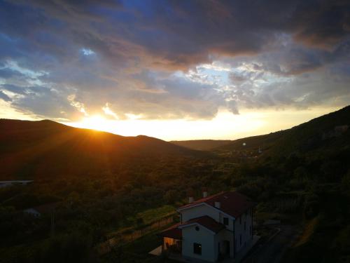 a sunset in the mountains with a house in the foreground at Apartma Čeh in Gabrovica pri Črnem Kalu