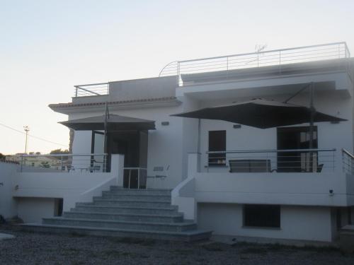a white building with stairs and an umbrella at Il Sogno di Calipso in Amendolara