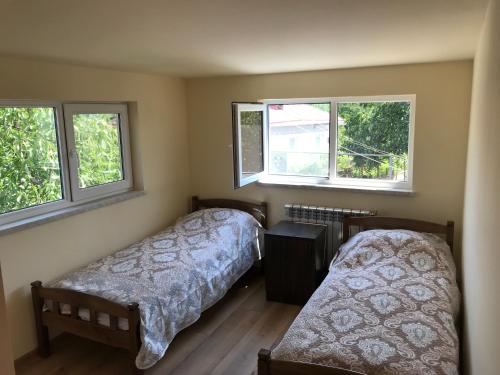 two beds in a room with two windows at COMMUNE hotel in Garni